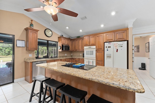6045 Whipoorwill Ln, Fort Pierce, FL 34987 - kitchen with black appliances, lofted ceiling, light tile patterned floors, a kitchen breakfast bar, and ornamental molding