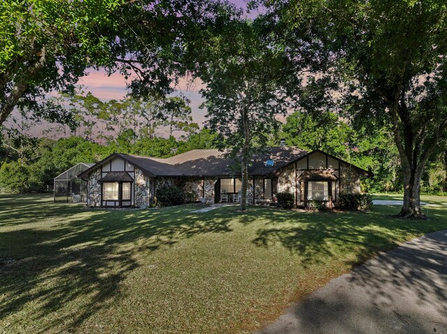 6045 Whipoorwill Ln, Fort Pierce, FL 34987 - view of front of home featuring stone siding, a front yard, and glass enclosure