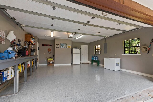 6045 Whipoorwill Ln, Fort Pierce, FL 34987 - garage featuring freestanding refrigerator, refrigerator, baseboards, and a garage door opener