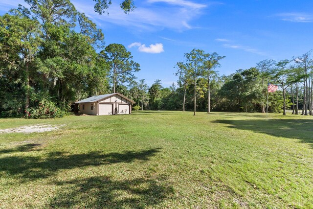 6045 Whipoorwill Ln, Fort Pierce, FL 34987 - view of green lawn featuring a detached garage and an outbuilding