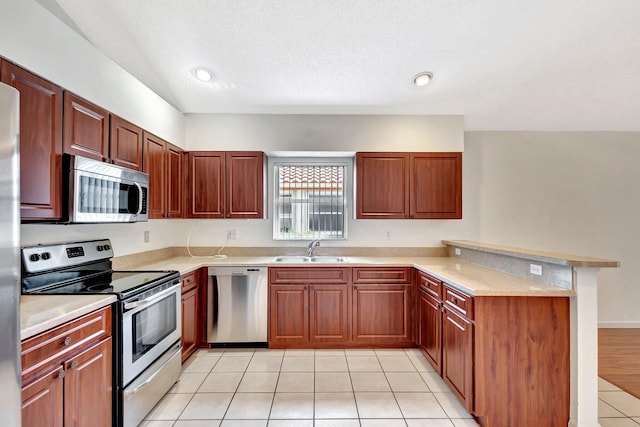 2445 Stonegate Dr, Wellington, FL 33414 - kitchen featuring a peninsula, light tile patterned flooring, light countertops, a sink, and stainless steel appliances