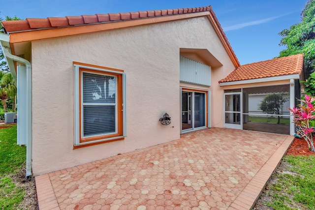 2445 Stonegate Dr, Wellington, FL 33414 - back of property with a sunroom, a tile roof, cooling unit, a patio, and stucco siding