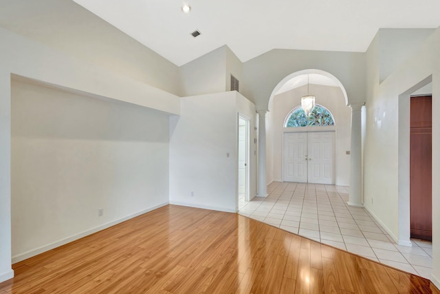 2445 Stonegate Dr, Wellington, FL 33414 - foyer with high vaulted ceiling, decorative columns, arched walkways, and light wood-style floors