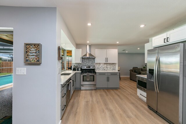 8421 NW 24th St, Sunrise, FL 33322 - kitchen featuring wall chimney range hood, backsplash, appliances with stainless steel finishes, light wood-type flooring, and light countertops