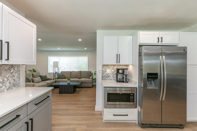 8421 NW 24th St, Sunrise, FL 33322 - kitchen with white cabinets, appliances with stainless steel finishes, light wood finished floors, and tasteful backsplash