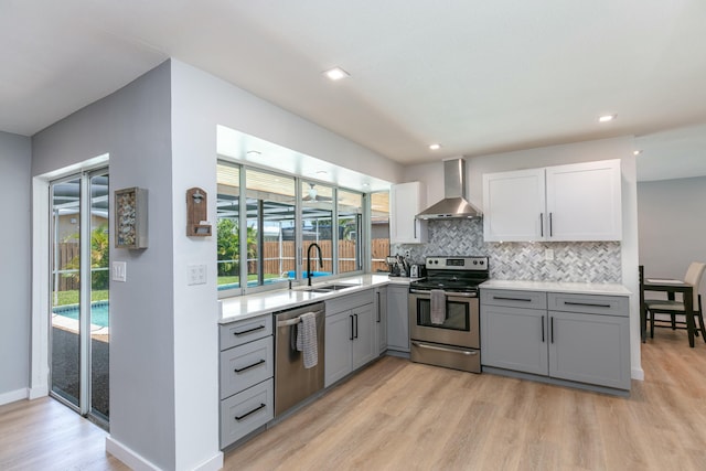 8421 NW 24th St, Sunrise, FL 33322 - kitchen featuring appliances with stainless steel finishes, a sink, light wood finished floors, wall chimney exhaust hood, and gray cabinetry