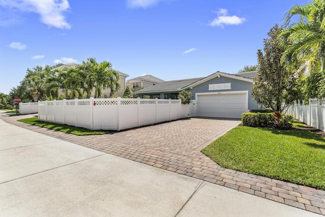 1345 Bourne Dr, Jupiter, FL 33458 - view of front of house with a front yard, a fenced front yard, a garage, stucco siding, and decorative driveway
