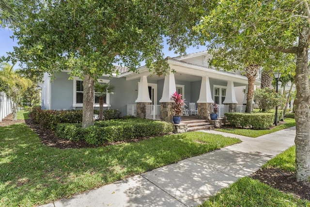 1345 Bourne Dr, Jupiter, FL 33458 - view of front of house with a front yard, central AC, a porch, stone siding, and stucco siding
