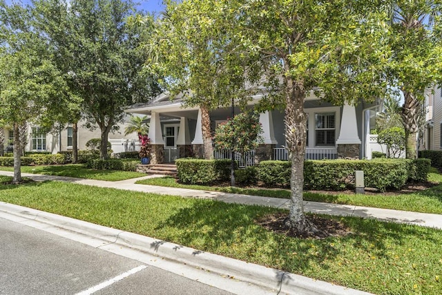 1345 Bourne Dr, Jupiter, FL 33458 - obstructed view of property featuring a porch, stucco siding, stone siding, and a front yard