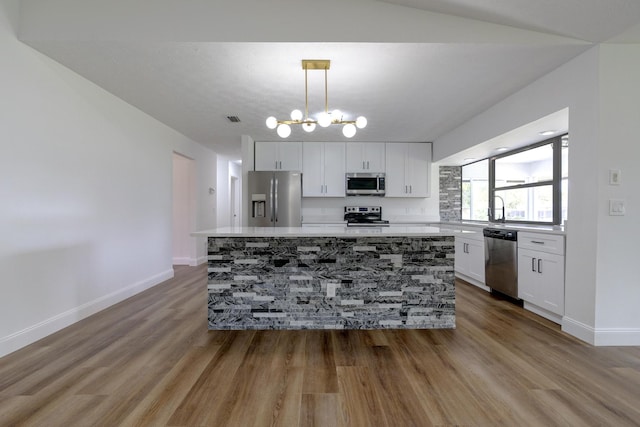 2381 SE Aneci St, Port Saint Lucie, FL 34984 - kitchen featuring appliances with stainless steel finishes, wood finished floors, white cabinets, light countertops, and a kitchen island