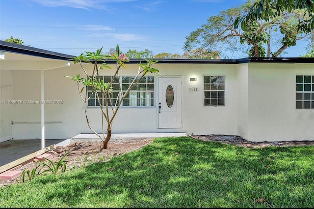 property entrance with a yard and stucco siding