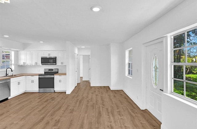kitchen featuring light wood-type flooring, white cabinets, recessed lighting, appliances with stainless steel finishes, and a sink