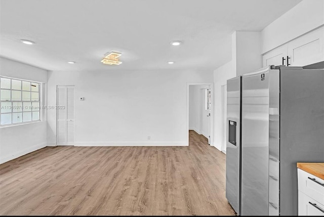 kitchen featuring white cabinets, baseboards, stainless steel fridge, light wood-type flooring, and recessed lighting