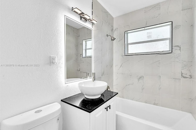 bathroom with washtub / shower combination, toilet, vanity, and a textured wall