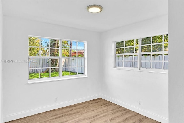 empty room featuring wood finished floors, baseboards, and plenty of natural light