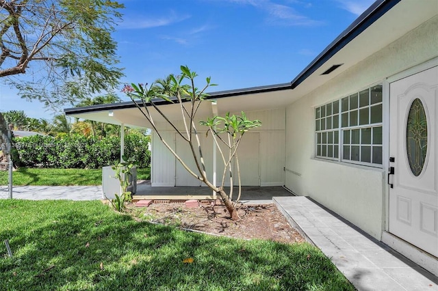 property entrance featuring a yard and stucco siding