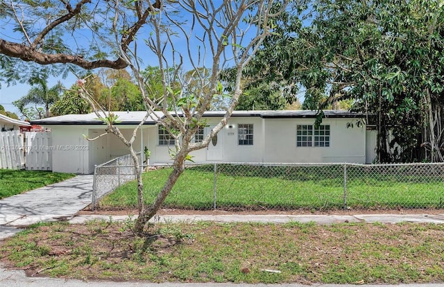 view of front of property with a fenced front yard, a front lawn, an attached carport, and concrete driveway