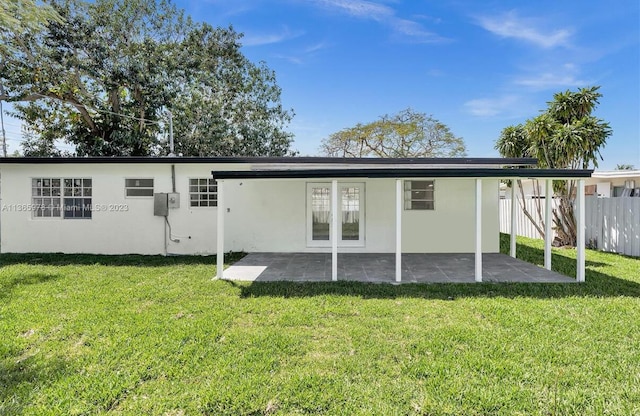 back of property featuring fence, a lawn, and stucco siding