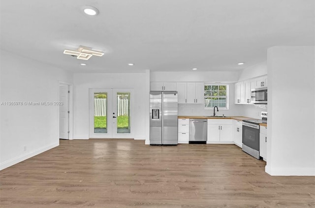 kitchen featuring light wood-style flooring, a sink, white cabinetry, and stainless steel appliances