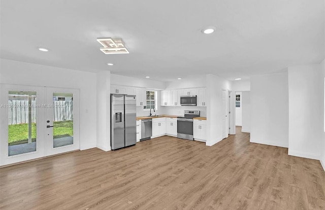 kitchen featuring a wealth of natural light, light wood-style flooring, white cabinetry, and appliances with stainless steel finishes