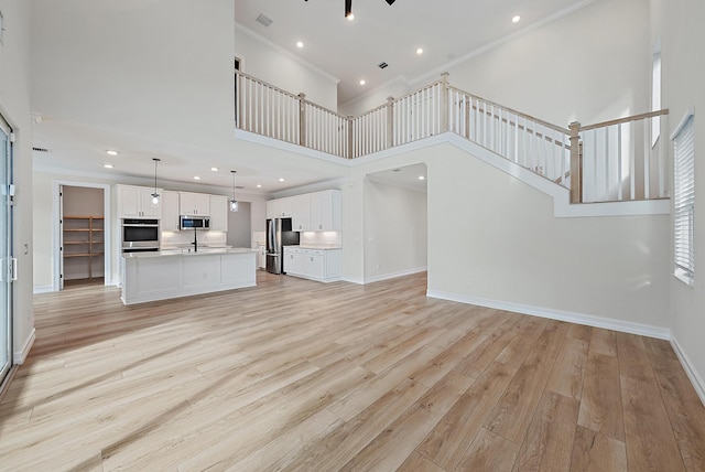4770 SW Ardsley Dr, Stuart, FL 34997 - unfurnished living room with crown molding, a towering ceiling, light wood-style floors, baseboards, and stairs