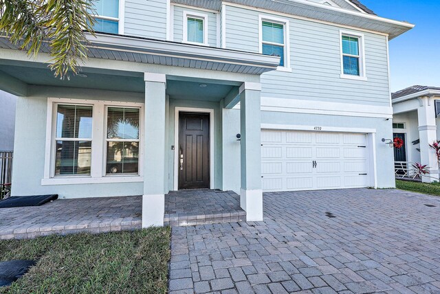4770 SW Ardsley Dr, Stuart, FL 34997 - doorway to property featuring an attached garage and decorative driveway
