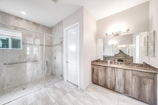 full bath featuring a stall shower, vanity, and baseboards