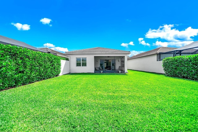 rear view of property with stucco siding, a ceiling fan, and a lawn