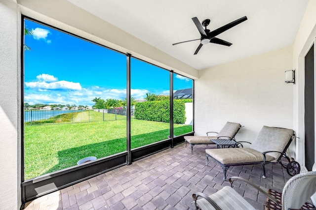 sunroom featuring a water view and a ceiling fan