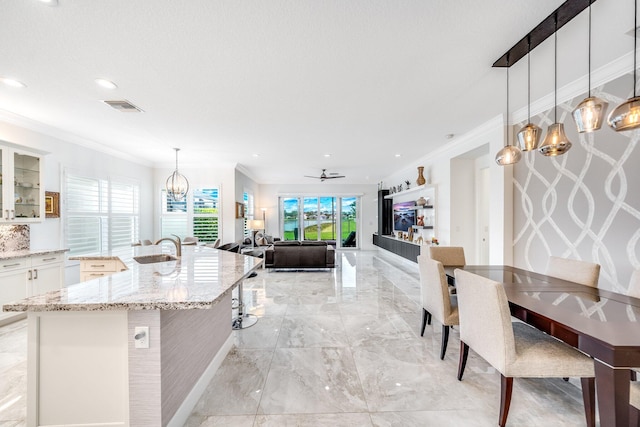 kitchen with visible vents, white cabinets, a sink, crown molding, and marble finish floor