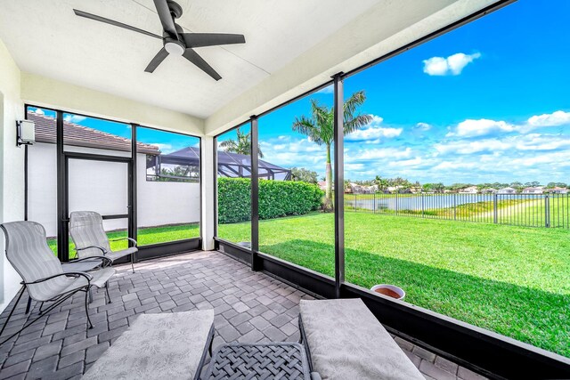 unfurnished sunroom featuring a water view and ceiling fan