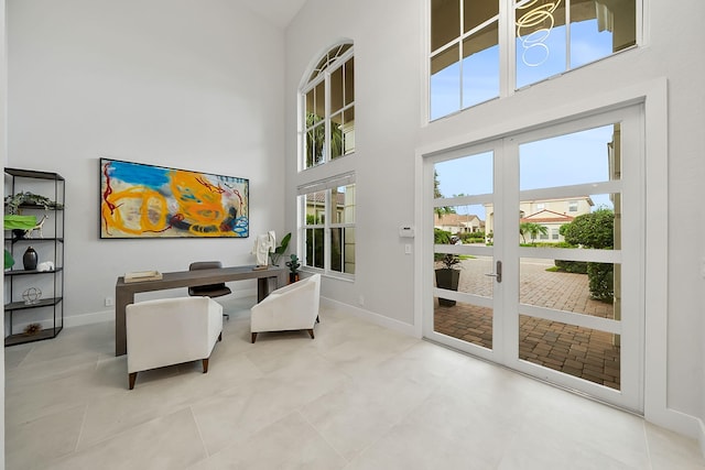 living area with baseboards and a high ceiling