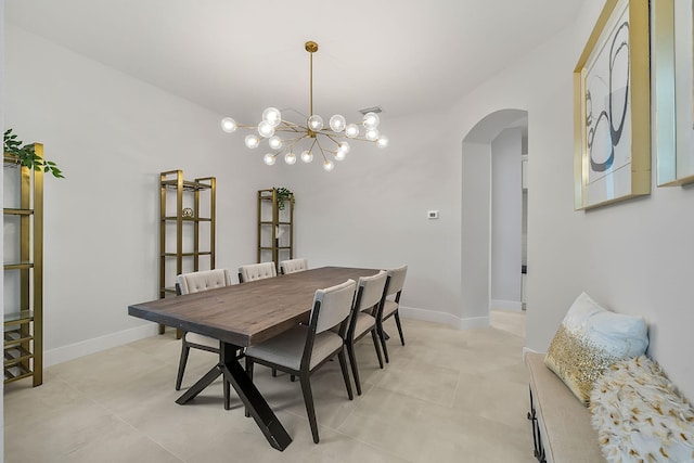 dining space with a chandelier, baseboards, and arched walkways