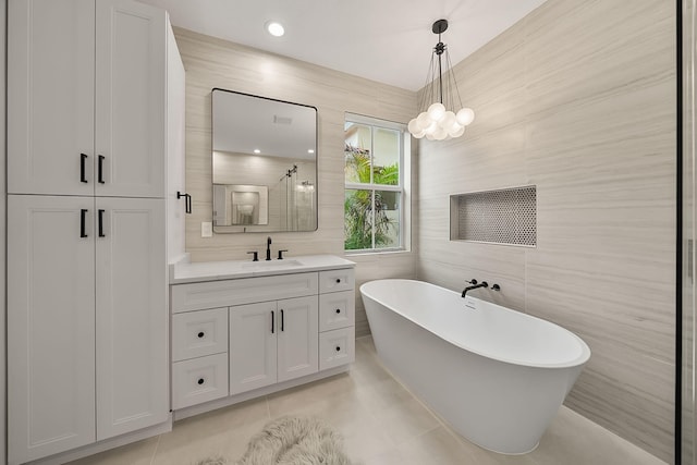 bathroom with tile patterned floors, tile walls, vanity, a soaking tub, and a stall shower