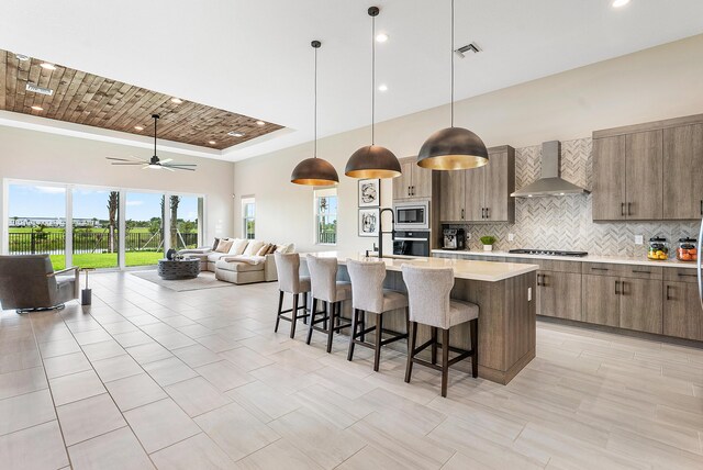 12618 Nautilus Cir, Palm Beach Gardens, FL 33412 - kitchen with wall chimney exhaust hood, open floor plan, light countertops, appliances with stainless steel finishes, and a breakfast bar area