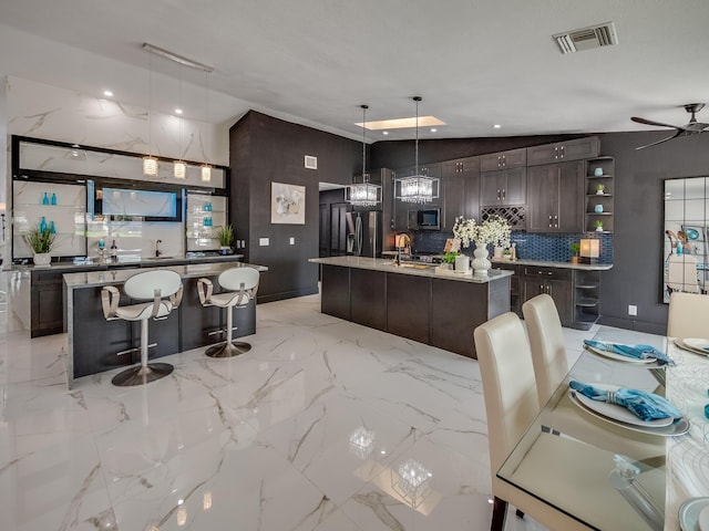 8540 Lake Cypress Rd, Lake Worth, FL 33467 - kitchen featuring dark brown cabinetry, visible vents, marble finish floor, stainless steel appliances, and a center island with sink