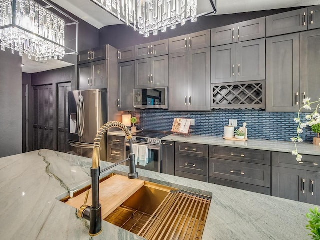 8540 Lake Cypress Rd, Lake Worth, FL 33467 - kitchen with tasteful backsplash, light stone countertops, a chandelier, and stainless steel appliances