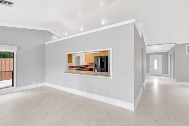 unfurnished living room with crown molding, a healthy amount of sunlight, light tile patterned floors, and visible vents
