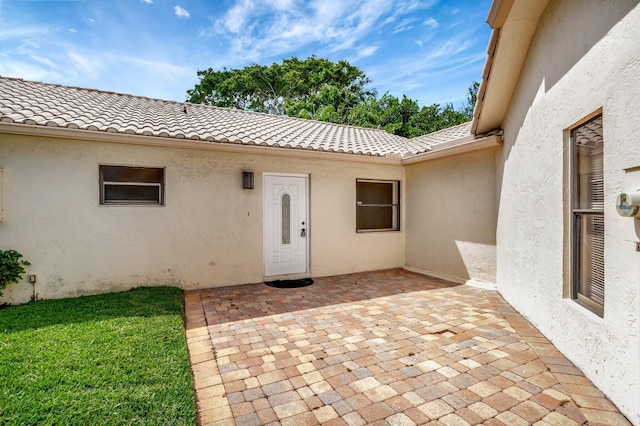 doorway to property with a patio area, stucco siding, and a tile roof