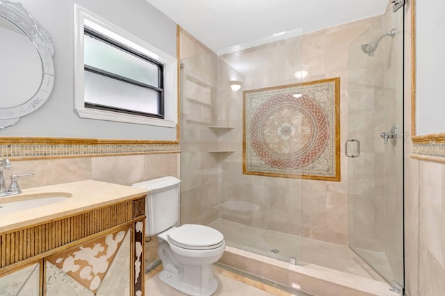 bathroom featuring vanity, a wainscoted wall, toilet, a shower stall, and tile walls