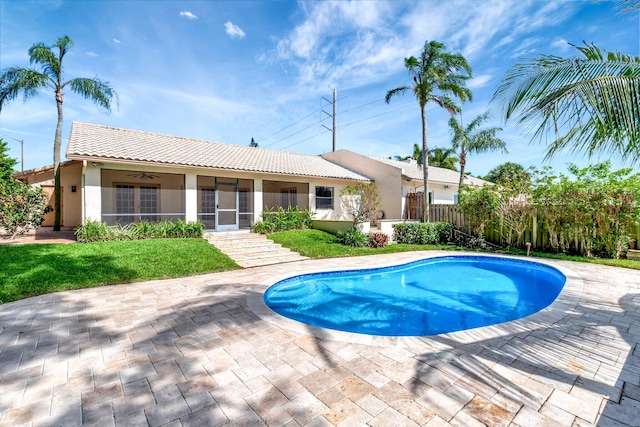 view of swimming pool with a sunroom, a fenced in pool, fence, and a lawn