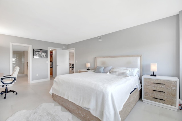 bedroom featuring baseboards, a spacious closet, visible vents, and ensuite bath