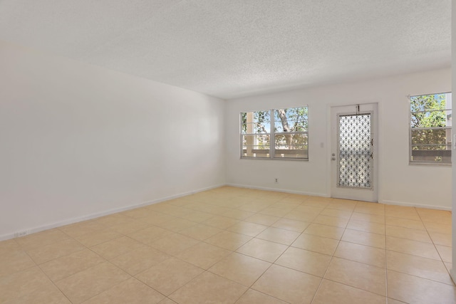 3034 Oakridge D 3034, Deerfield Beach, FL 33442 - empty room featuring plenty of natural light, a textured ceiling, light tile patterned floors, and baseboards