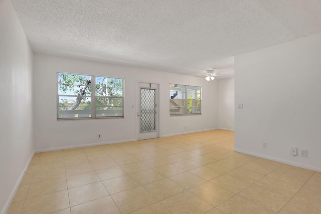 3034 Oakridge D 3034, Deerfield Beach, FL 33442 - empty room featuring healthy amount of natural light, a textured ceiling, ceiling fan, light tile patterned floors, and baseboards