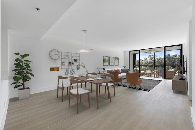 dining room featuring light wood-type flooring, baseboards, and a wall of windows