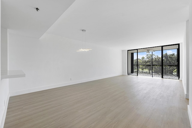 empty room featuring baseboards, light wood-type flooring, and floor to ceiling windows