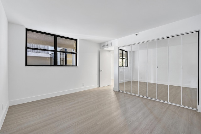 unfurnished bedroom featuring a closet, light wood-style floors, and baseboards