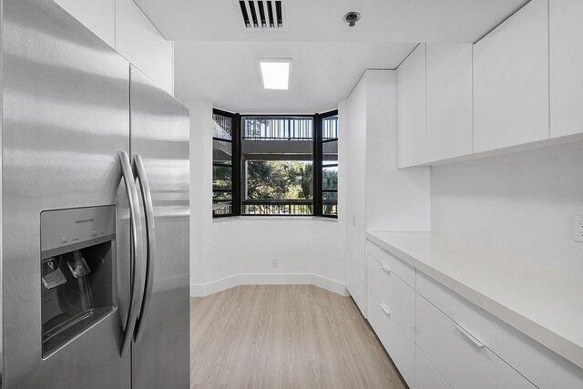 kitchen featuring stainless steel fridge with ice dispenser, visible vents, light countertops, white cabinetry, and light wood-style flooring