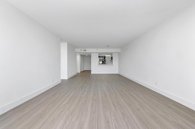 unfurnished living room featuring light wood finished floors and baseboards