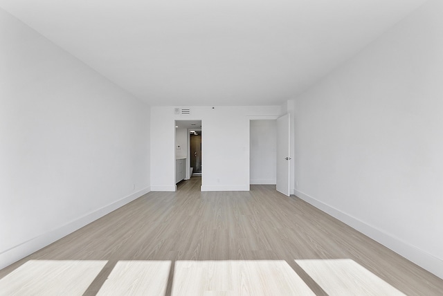 empty room featuring light wood-style floors, baseboards, and visible vents